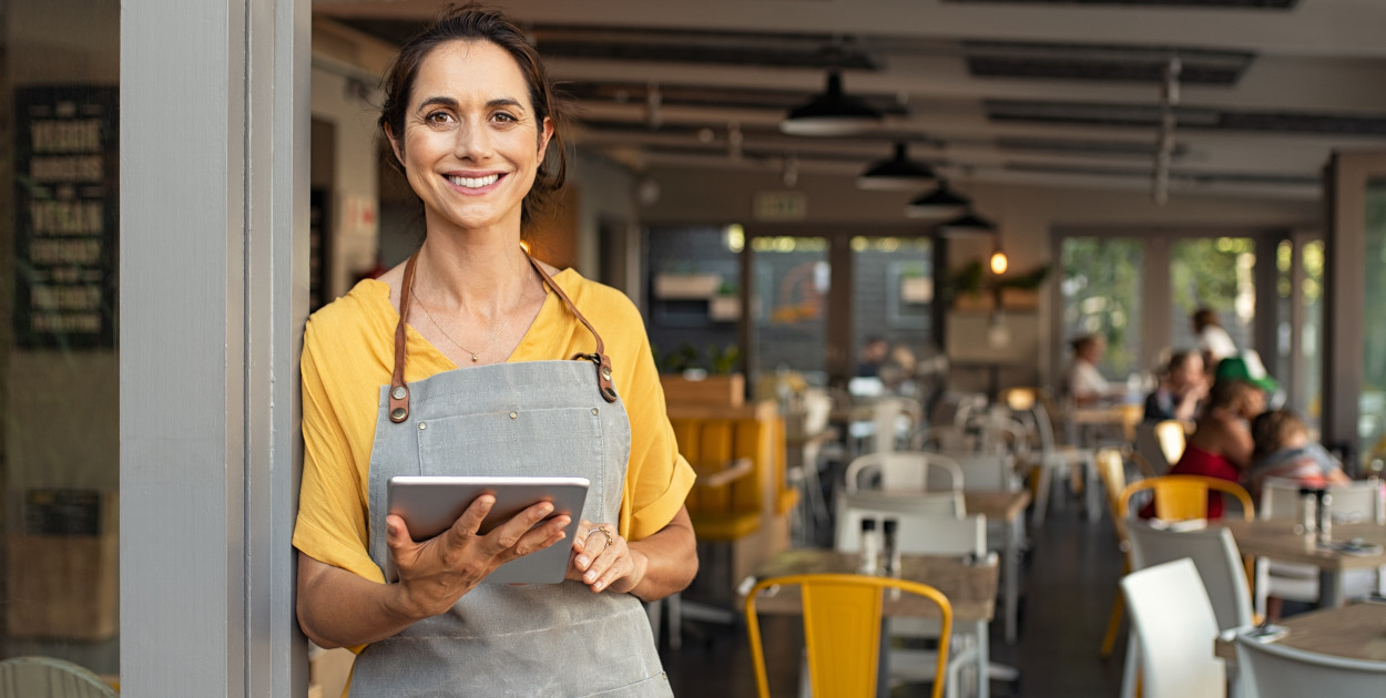 Kobieta pracująca w restauracji sprawdzająca rezerwację na tablecie